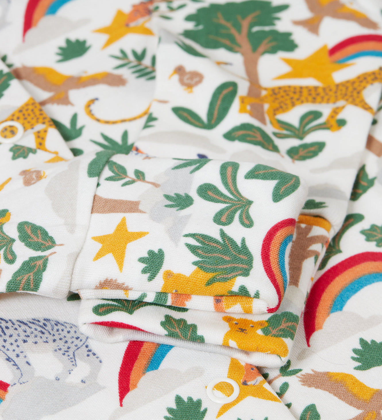 A close up of the fold over cuffs on the babygrow from the Frugi Into The Wild Organic Cotton Babygrow Gift Set. The set comes with a white babygrow covered with the into the wild all over print and a grey bandana style bib with an applique of a cheetahs face on it.
This gift set is a part of a wide range of organic cotton clothing for children available here at Babipur. 
