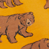 A close up of the Frugi kids beary wild parsnip joggers showing the bear print detail on dark yellow organic cotton fabric.