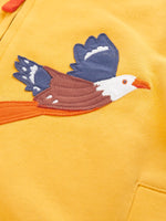 Close up of the eagle applique on the Frugi organic cotton blaire zip hoodie in bumblebee yellow. 
