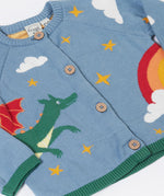 A close up of the front of the Frugi Organic Cotton Reva Dragon Skies Knitted Kids' Cardigan. This blue cardigan features a fun, colourful design featuring a green dragon, stars, rainbow, clouds and a mushroom. This cardigan is a part of a wide range of organic cotton clothing for children available here at Babipur. 