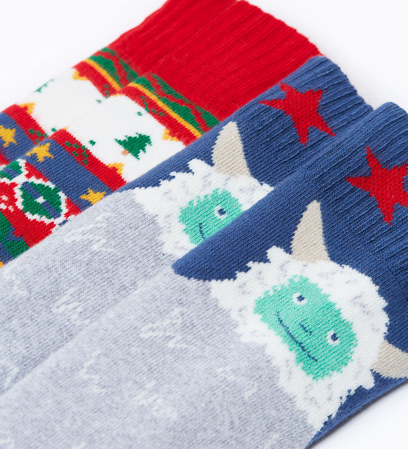 A close up of the 2 pack of Frugi Brilliant Boot organic cotton kids Socks. One pair has a yeti design, one has a fairisle design. These Christmas socks are part of a wide range of organic cotton clothing for children available here at Babipur. 