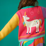 Back of a child wearing the Frugi organic cotton cammie cardigan showing the large unicorn on the back with a rainbow dress underneath.