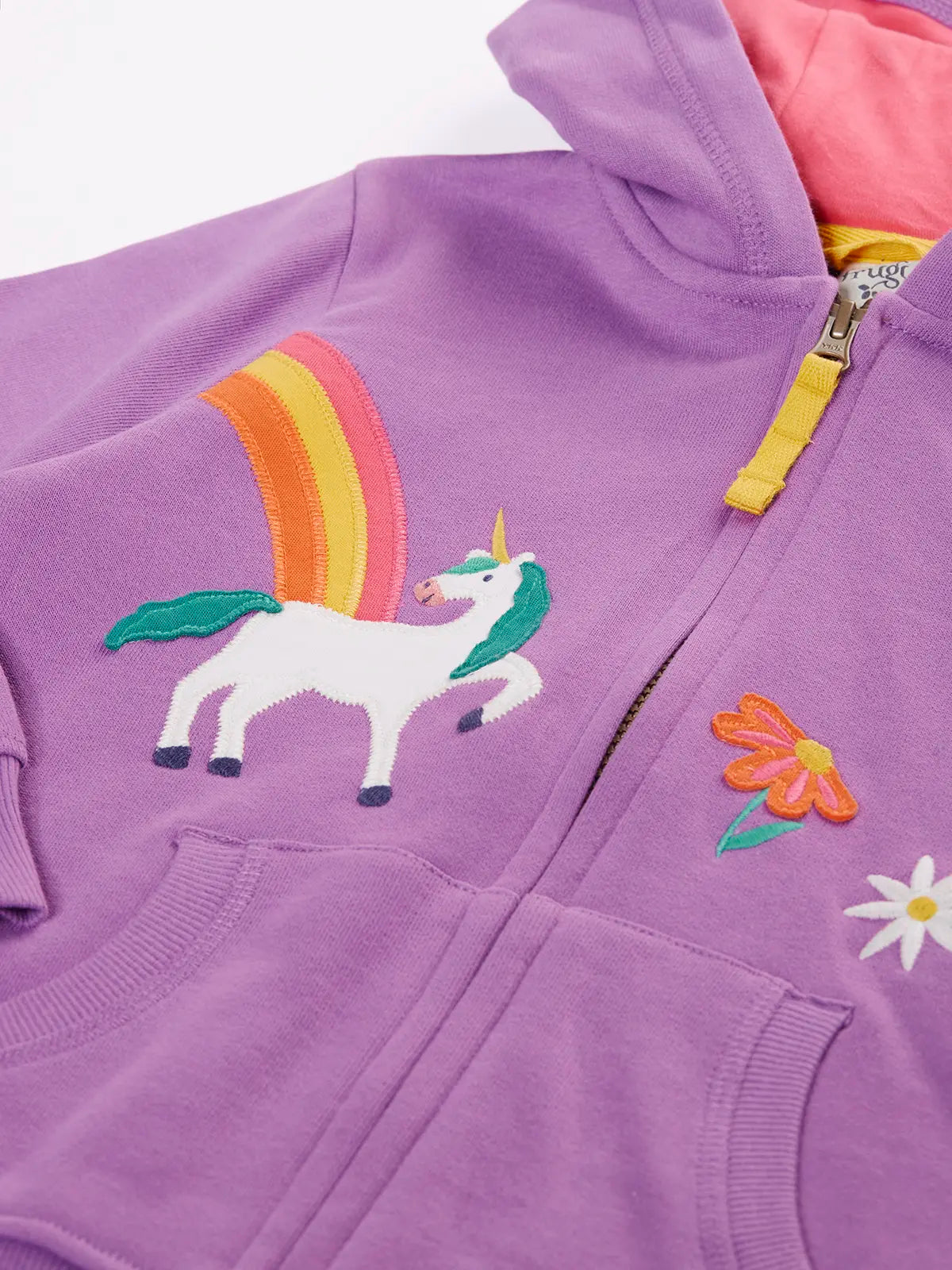 Close up of unicorn, rainbow and flower appliues on teh front of the Frugi organic cotton purple periwinkle carbis zipped children's hoodie.