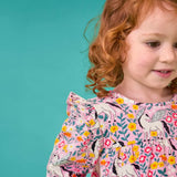 Close up of a frilled shoulders on the top from the Frugi organic cotton Charlotte outfit. All over floral flight, frilled shoulder long sleeve top with rhubarb pink leggings.