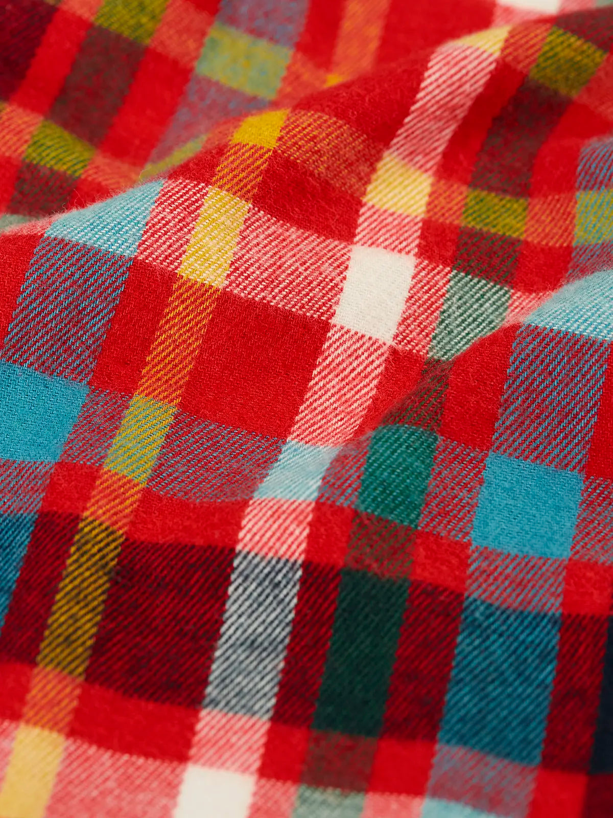 Close up of the multi coloured check material trousers from the Frugi organic cotton caden check festive fox pyjamas.