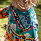 Close up of the wooden buttons on the shoulder of the Frugi festive fair isle organic cotton jumper worn by a child.