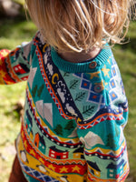 Close up of the wooden buttons on the shoulder of the Frugi festive fair isle organic cotton jumper worn by a child.