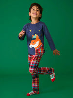 Child wearing the Frugi organic cotton caden check festive fox pyjamas. Long sleeved navy top with fox applique with multi coloured check trousers. 
