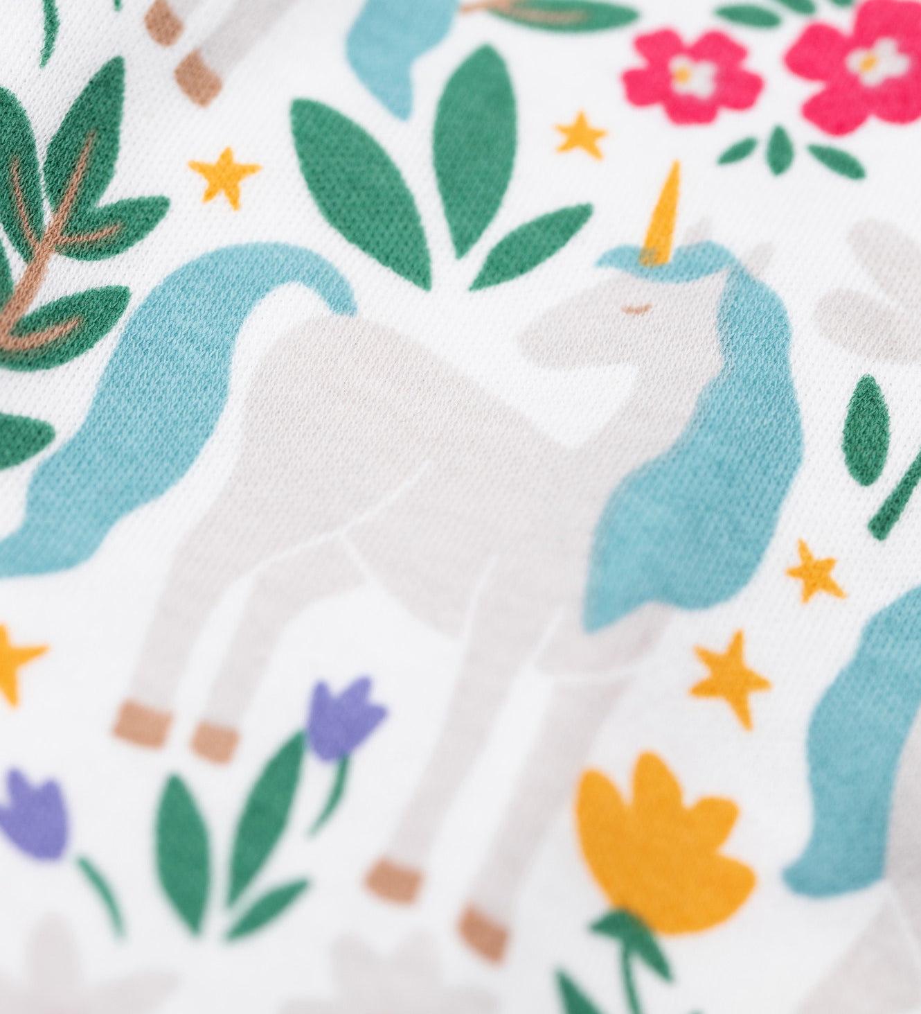 A close up of the print on the trousers from the Frugi Organic Cotton Alana navy unicorn forest print children's Pyjamas. These pyjamas are part of a wide range of organic cotton clothing for children available here at Babipur. 