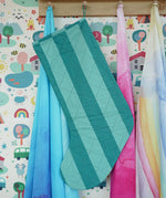 Back of the Frugi organic cotton Christmas stocking. Striped teal quilted style stocking hung up on a wooden shelf in the Babipur playroom.