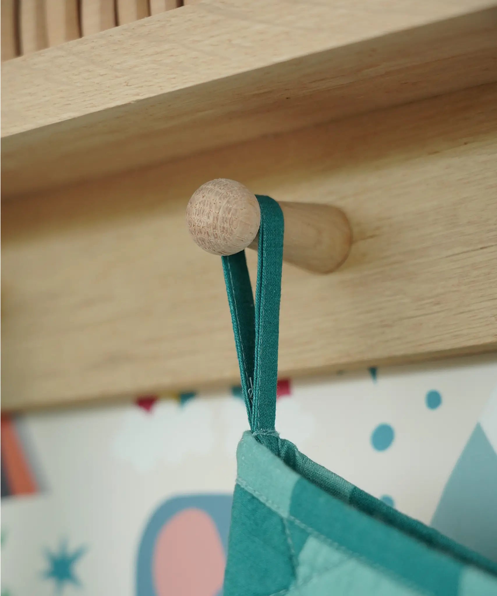 Close up of the hanging loop on the Frugi organic cotton Christmas stocking. Striped teal quilted style stocking with a robin wreath embroidery detail on teh front.
