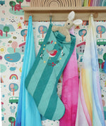 Frugi organic cotton Christmas stocking. Striped teal quilted style stocking with a robin wreath embroidery detail and hanging loop hung up in the Babipur playroom with a Senger rabbit soft toy inside.