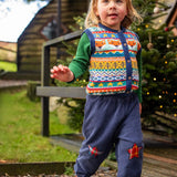 Child wearing the Frugi fox fair isle organic cotton wenn knitted waistcoat. Multi-coloured fair isle knit with navy edges with navy cord festive star trousers. 