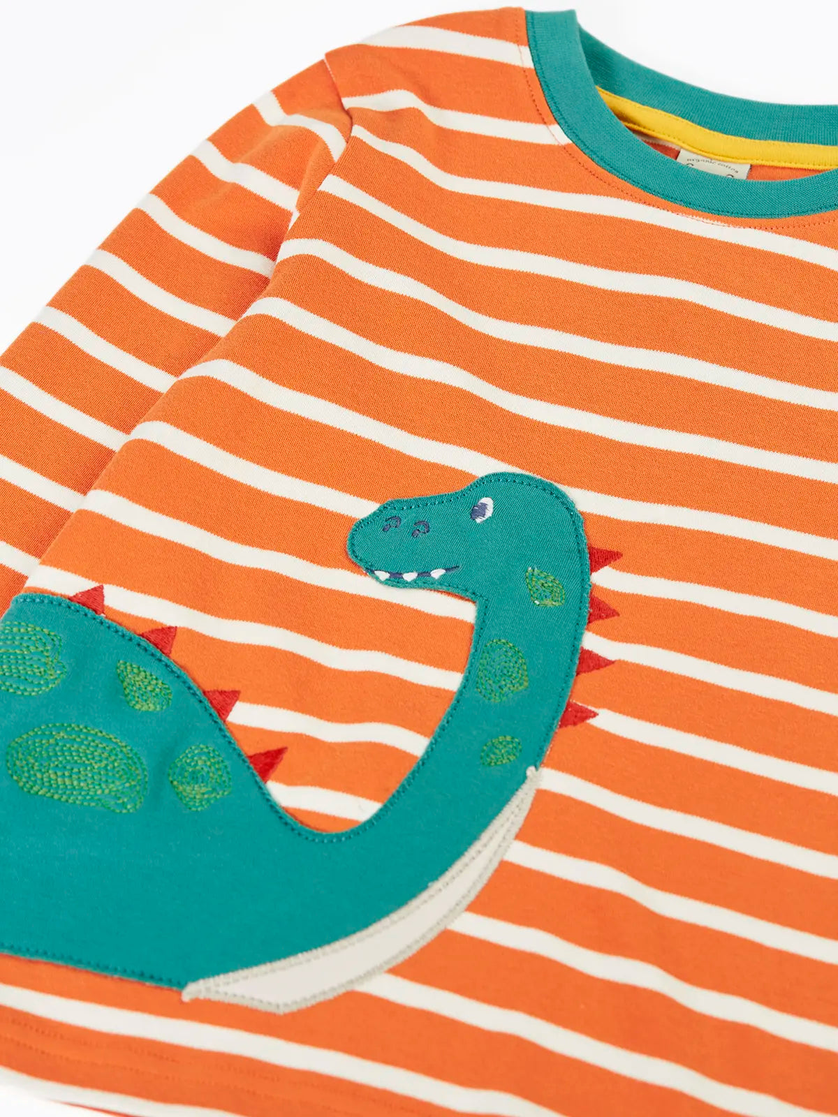 Close up of the teal nessie on the Frugi organic cotton felix long sleeve orange breton stripe top.