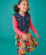 Child wearing the Frugi organic cotton connie navy knitted waistcoat with embroidered flower details, wooden button closure and scalloped edges with a pink long sleeve top underneath and a Marta Twill Skirt with flower stamps design.