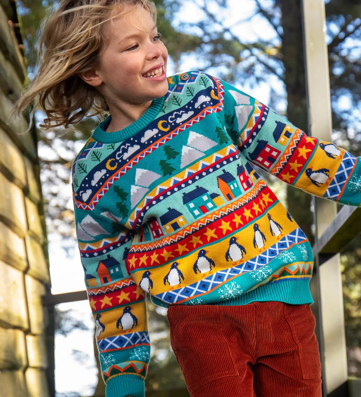 Child wearing a Frugi festive fair isle organic cotton jumper with rust corduroy trousers.