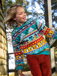 Child wearing a Frugi festive fair isle organic cotton jumper with rust corduroy trousers.