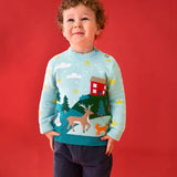 Child wearing the Frugi organic cotton elwood knitted jumper with a Winter tales design. Light blue long sleeved jumper with a landscape design on the front featuring a red house, snowman, reindeer, fox, trees and snow and stars with navy blue corduroy trousers.