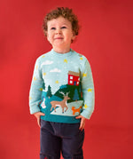 Child wearing the Frugi organic cotton elwood knitted jumper with a Winter tales design. Light blue long sleeved jumper with a landscape design on the front featuring a red house, snowman, reindeer, fox, trees and snow and stars with navy blue corduroy trousers.