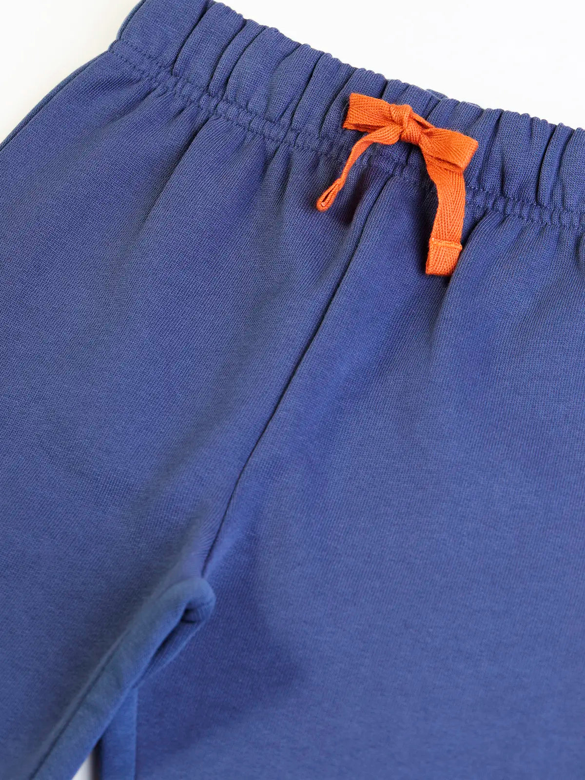 Close up of the elasticated waist and orange waist tie on the Frugi navy nessie organic cotton kids character joggers.