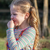 A little girl wearing a Frugi organic cotton kids' outfit featuring the Lucia stripy top.