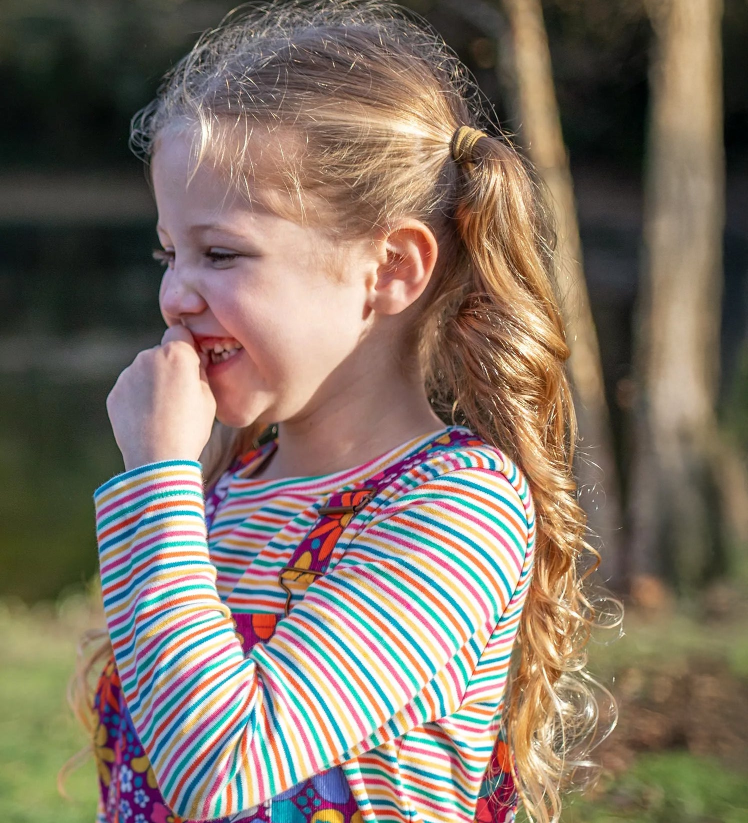 A little girl wearing a Frugi organic cotton kids' outfit featuring the Lucia stripy top.