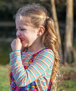 A little girl wearing a Frugi organic cotton kids' outfit featuring the Lucia stripy top.