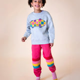 A little girl wearing an organic cotton frugi kids' outfit - an embroidered sweater and pink Malpas joggers.