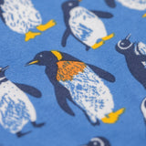 A close up of the print on the Frugi organic cotton kids libby leggings with a penguin waddle print on a blue background.