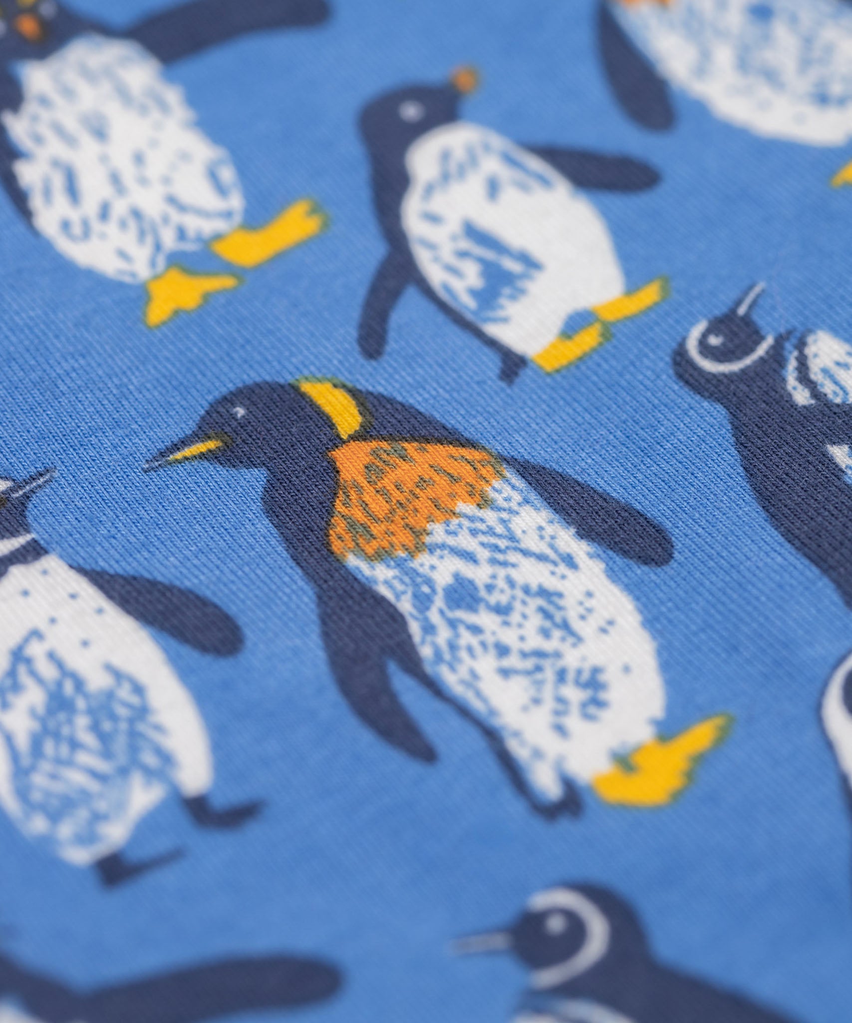 A close up of the print on the Frugi organic cotton kids libby leggings with a penguin waddle print on a blue background.