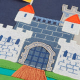 Close up of the embroidered brick detail on the castle applique on the Frugi childs organic cotton terrific long sleeve navy top.