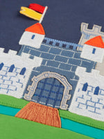 Close up of the embroidered brick detail on the castle applique on the Frugi childs organic cotton terrific long sleeve navy top.