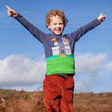 Child wearing the Frugi childs organic cotton terrific long sleeve navy top with castle applique with rust brown trousers.