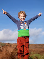 Child wearing the Frugi childs organic cotton terrific long sleeve navy top with castle applique with rust brown trousers.