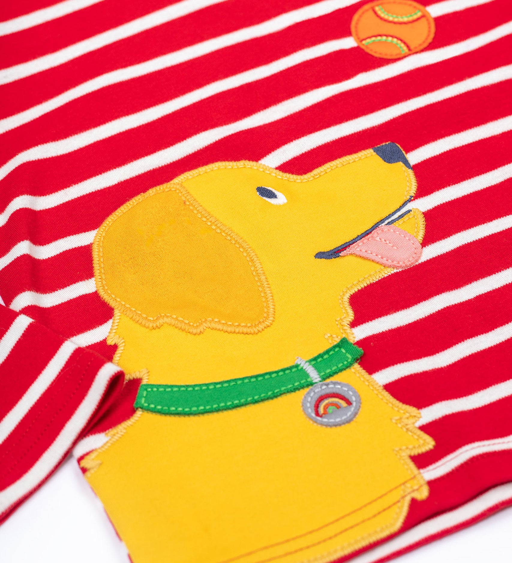 A close up of the yellow dog applique on the front of the Frugi Discovery Organic Cotton Circular Kids' Top with a red and white Breton Stripe.