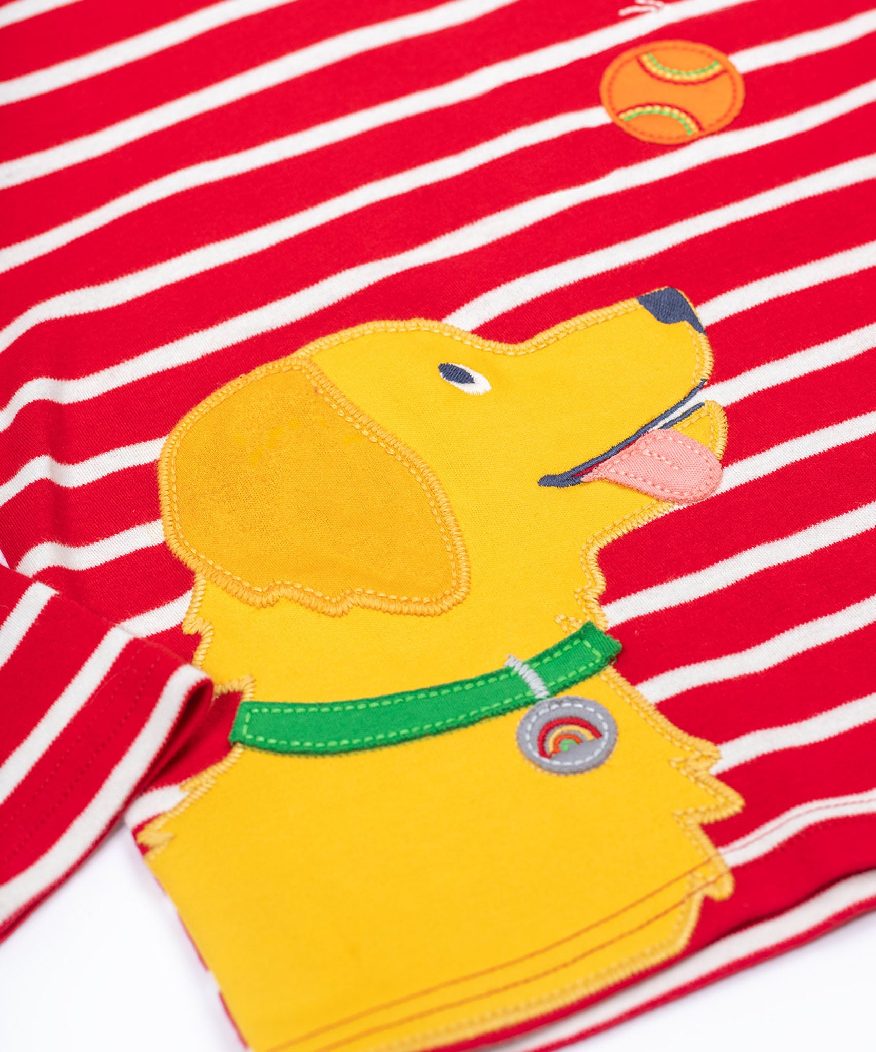 A close up of the yellow dog applique on the front of the Frugi Discovery Organic Cotton Circular Kids' Top with a red and white Breton Stripe.