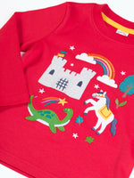 Close up of Frugi red organic cotton adventure magic applique long sleeved top with castle, rainbow, tree horse and nessie appliques on the front. 