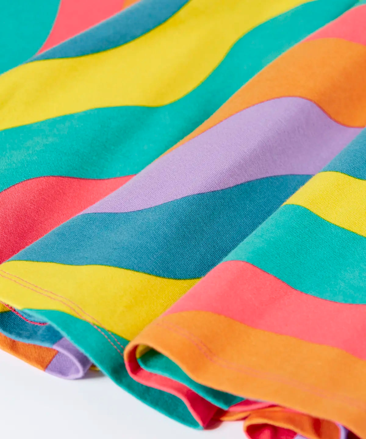Close up of the Frugi GOTS organic cotton long sleeved sofia skater dress with a rainbow ric rac pattern.