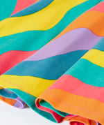 Close up of the Frugi GOTS organic cotton long sleeved sofia skater dress with a rainbow ric rac pattern.