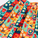 Close up of the Frugi organic cotton marta twill flower stamps skirt. Multi coloured rectangles with flowers. 