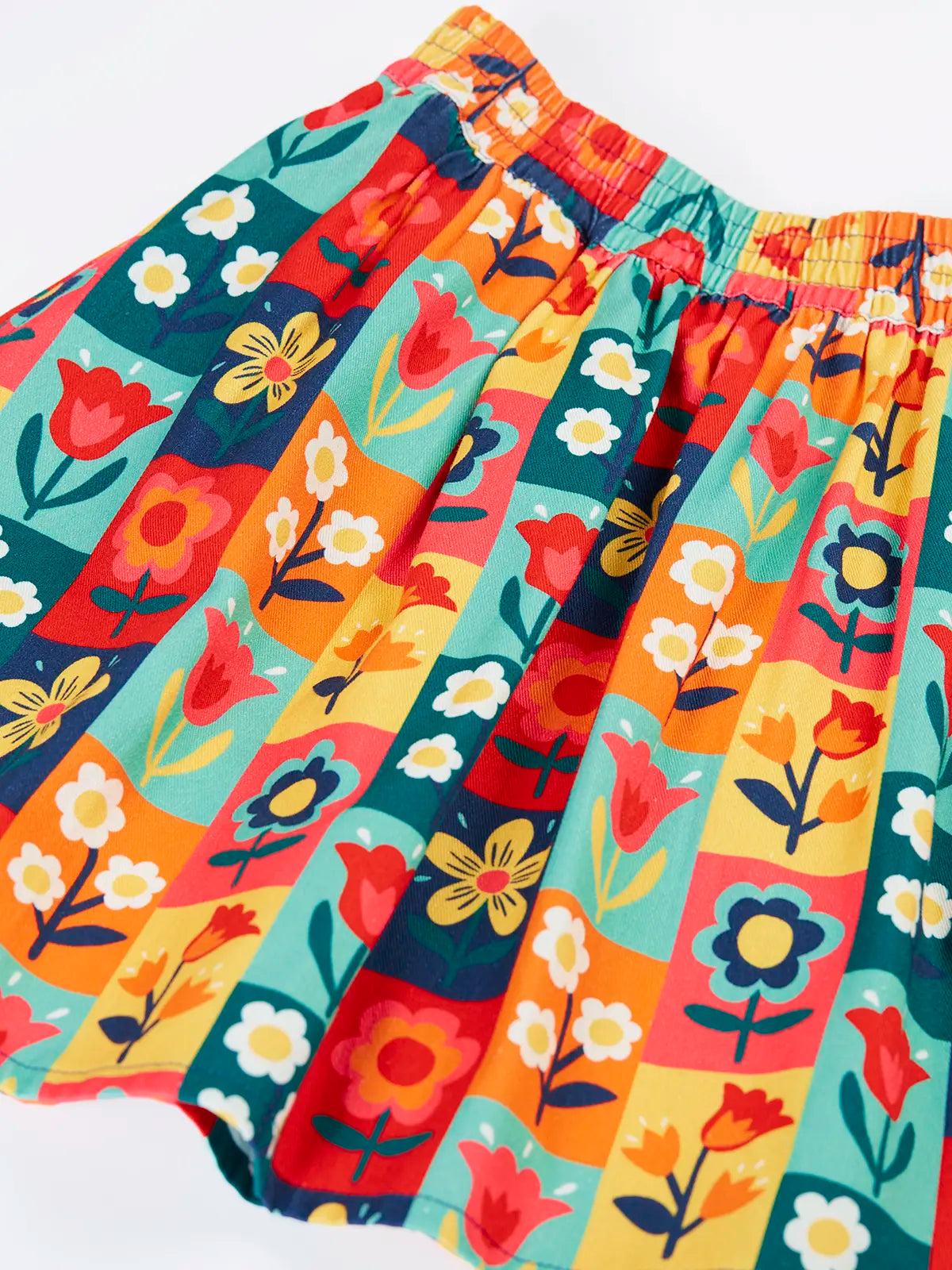 Close up of the Frugi organic cotton marta twill flower stamps skirt. Multi coloured rectangles with flowers. 
