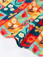 Close up of the hemline of the Frugi organic cotton marta twill flower stamps skirt. Multi coloured rectangles with flowers. 