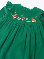 Close up of the robin, mistltoe, holly and toadstool festive details on the front of the Frugi organic cotton maud holly green corduroy dress.