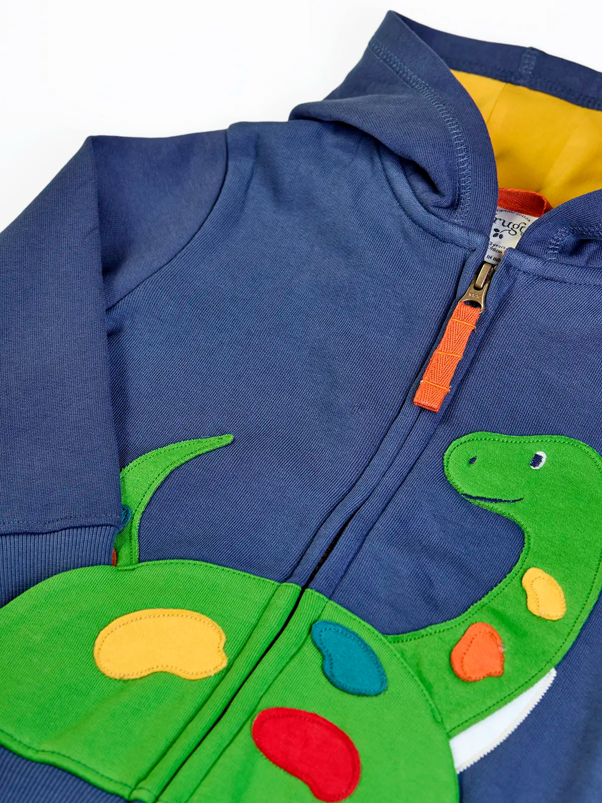 Close up of the green nessie applique on the front of the Frugi organic cotton carbis navy kids hoodie. The zip has an orange pull tab.