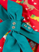 Close up of the poppers on the detachable teal bow that comes with the Frugi organic cotton pink party skater dress in a pet paw-ty print.