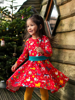 Child twirling wearing the Frugi organic cotton pink party skater dress in a pet paw-ty print featuring pets wearing party hats surrounded by wrapped gifts and balloons. 