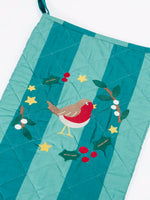 Close up of the Frugi organic cotton christmas stocking. Striped teal quilted style stocking with a robin wreath applique detail and hanging loop.