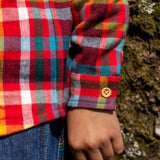 Child wearing Frugi organic cotton festive check hector long sleeve shirt with chest pocket. Close up of button on the sleeve cuffs.