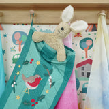 Close up of Senger rabbit soft toy in the Frugi organic cotton Christmas stocking. Striped teal quilted style stocking with a robin wreath embroidery detail and hanging loop hung up in the Babipur playroom.