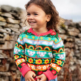 Child wearing the Frugi Robyn fairisle cardigan with a mouse Fair Isle design featuring flowers, rainbows, clouds and suns. 